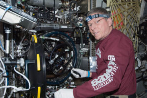 Col. Michael Fossum tinkering with a large mechanical display.